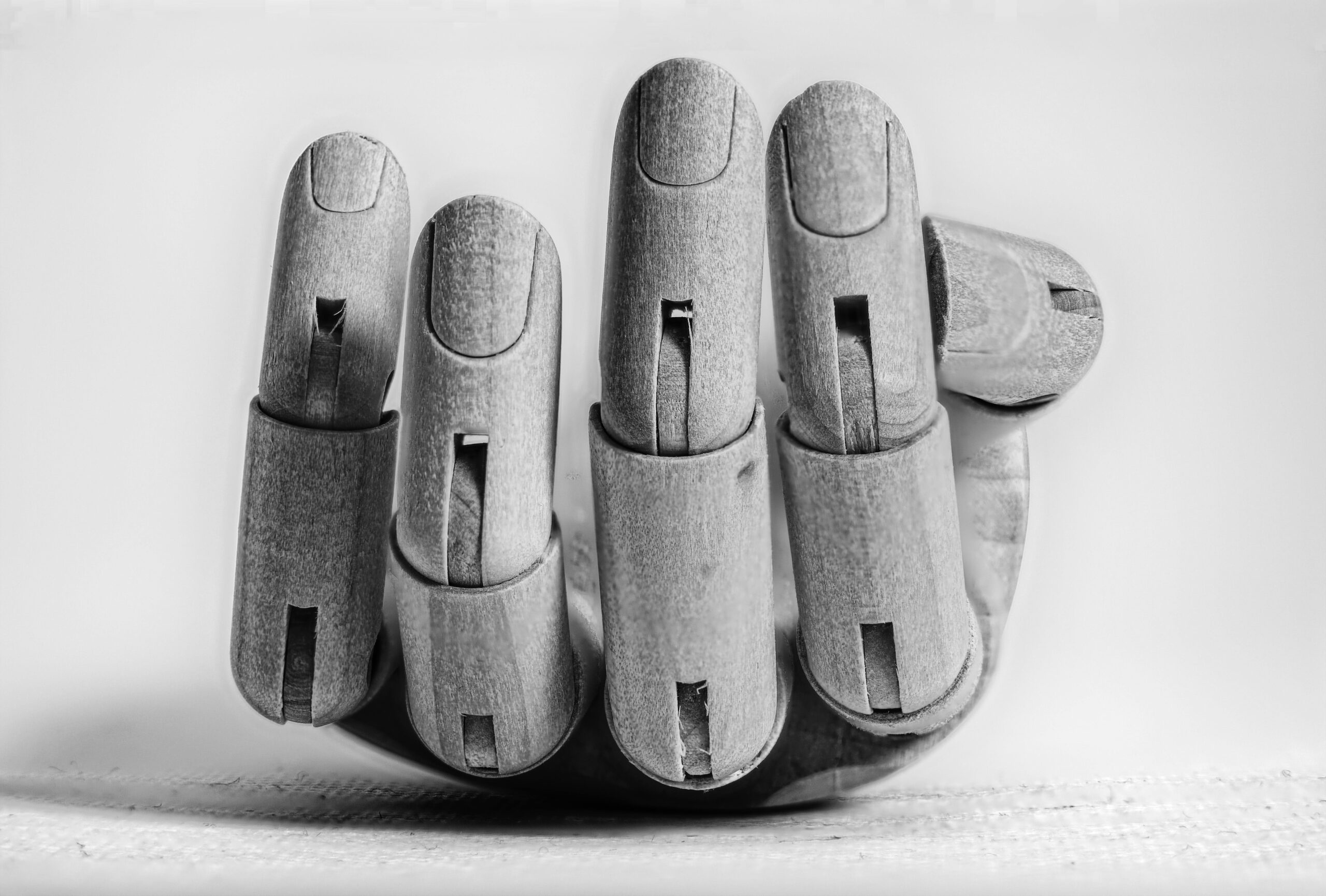 Close-up image of a wooden articulated hand model showing detailed fingers on a textured surface.
